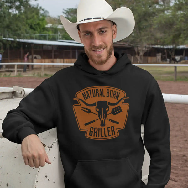 Man in ’Natural Born Griller’ black hoodie and cowboy hat, outdoor-ready style